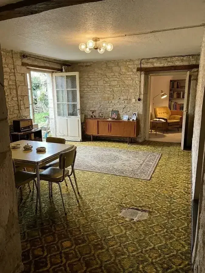Séjour ancien avant travaux : moquette à motifs, plafond crépi, mobilier d'époque et fils électriques apparents