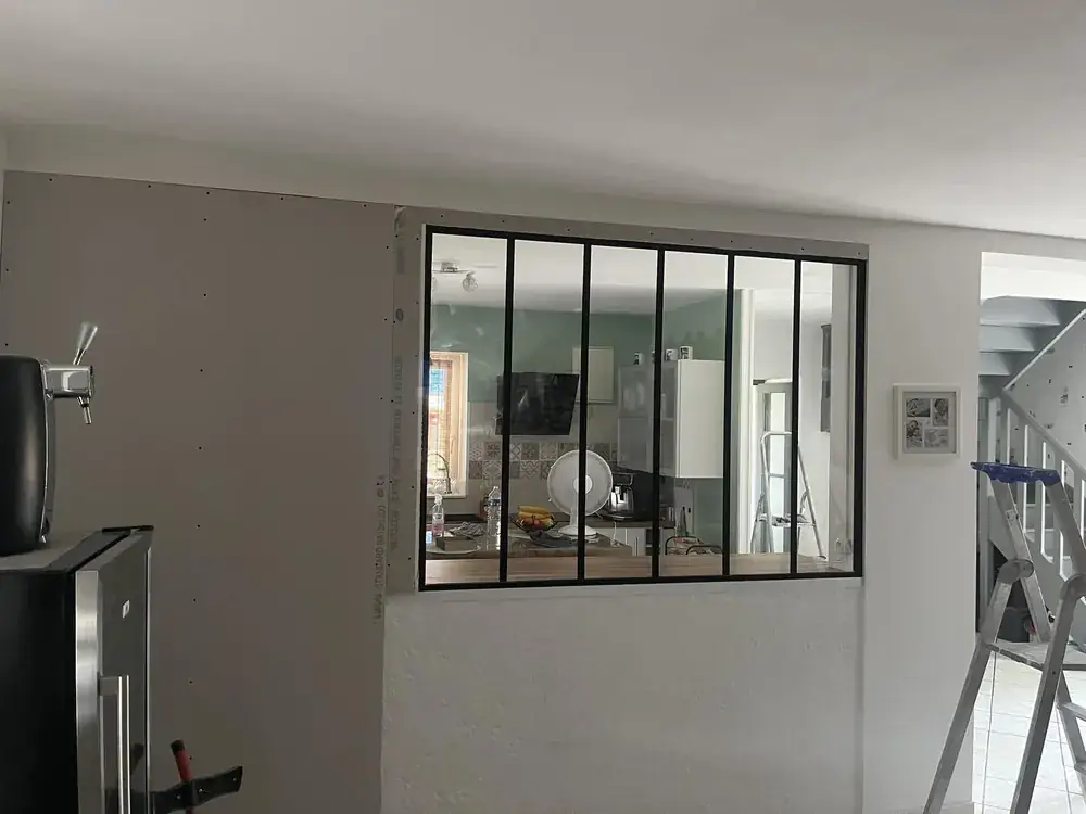 Cloison vitr&eacute;e de type atelier mont&eacute;e en pl&acirc;trerie, s&eacute;parant deux espaces int&eacute;rieurs