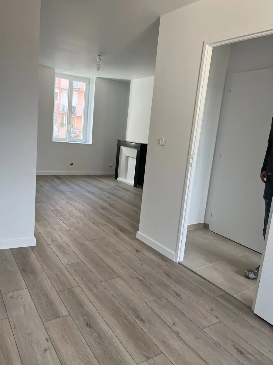 Appartement r&eacute;nov&eacute; : murs blancs, sol stratifi&eacute; gris et chemin&eacute;e conserv&eacute;e