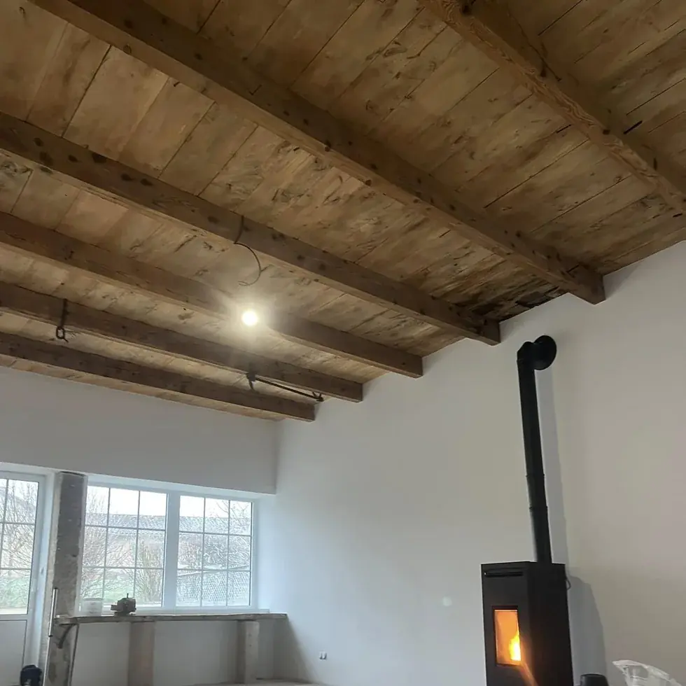 Volume ancien terminé : plafond à solives et planches conservé, murs repris et lissés en blanc, poêle installé
